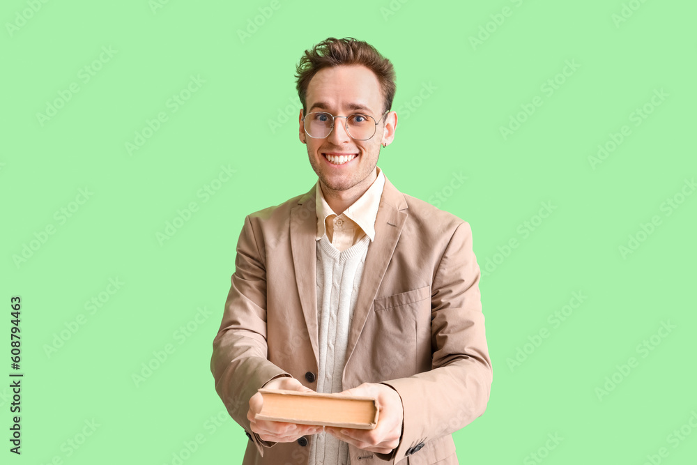 Young man with book on green background