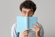 © Pixel-Shot - Male student reading book on light background, closeup