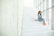 © BGStock72 - Young business woman sitting on the stairs on office hallway and working on laptop