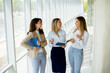 © BGStock72 - Three young business women having a discussion while walking in the office hallway