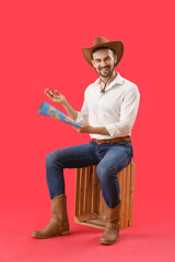 Wall Mural - Handsome cowboy with compass and world map sitting on red background