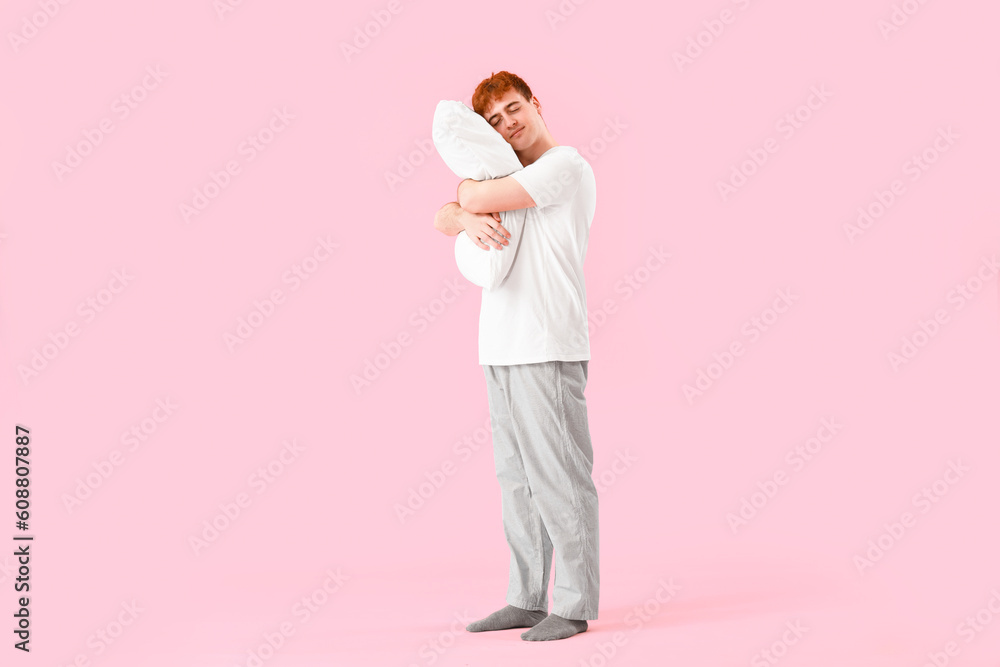 Young man with soft pillow on pink background