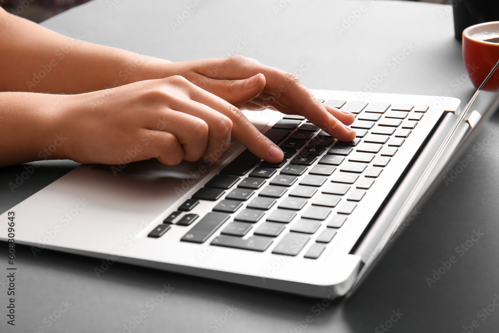 Female programmer working with laptop on dark table, closeup