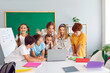 canvas print picture - Small group of happy positive excited smart school children have class with cheerful teacher, gather at laptop computer on desk table, look at new data, play interesting games, develop skills together