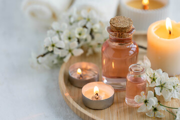 Burning candles, spa setting, essential oils, organic pure aromatic ingredients, atmosphere of relax. Aromatherapy, cozy home decor concept. Perfumery bottles, elegant composition with spring flowers