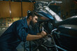 © Nomad_Soul - Man repairing motorcycle using wrench while working at repair workshop