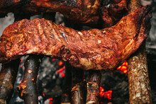A Slab Of Pork Ribs Cooking On Hot Coals In An Outdoor Setting