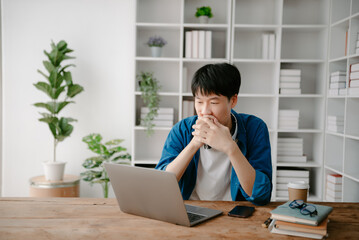 Male students note from the books at the Asian man library sitting at the desk using laptop computer and tablet to search an online informations.