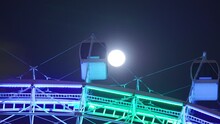 A Ferris Wheel Carriage Passing In Front Of A Full Moon In Orlando Florida. 