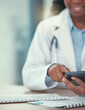 © M Dharsey/peopleimages.com - Phone, doctor and hands of black woman texting for telehealth, healthcare or research in hospital. Smartphone, medical professional or happy person with online consultation, reading email or wellness
