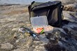  Box with bait , spinning,fisherman's bag on the rocky shore near the lake.