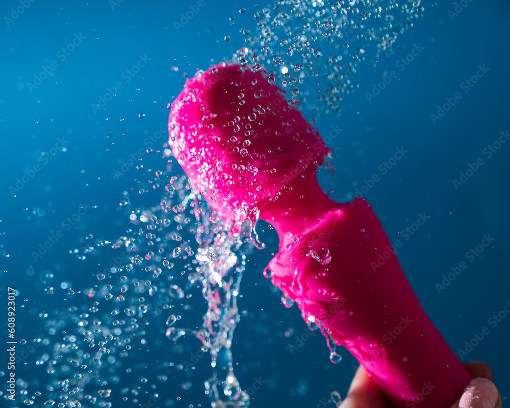 A woman washes a pink vibrator under running water on a blue background. Sex  toy hygiene concept. Stock Photo | Adobe Stock