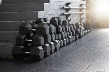 Equipment, gym weights and floor of room or empty facility for fitness, sports and exercise club mockup. Dumbbells, barbell stack and weight rack in a dark training gymnasium for workout class