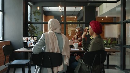 Wall Mural - Collaborating through video conference: Female business team having an online meeting in a coworking office