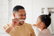© K.A./peopleimages.com - Father, child and brushing teeth in a family home bathroom for dental health and wellness in a mirror. Happy african man and girl kid learning to clean mouth with a toothbrush for oral hygiene