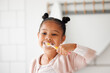 Toothbrush, brushing teeth and child in a home bathroom for dental health and wellness. Face of african girl kid cleaning mouth with a brush in a mirror for morning routine and oral self care