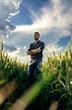 © Zoran Zeremski - Young farmer standing in a green wheat field examining crop.