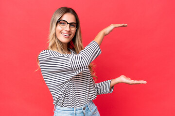 Wall Mural - Young Uruguayan woman isolated on red background holding copyspace to insert an ad