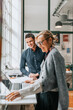 © Maskot - Happy male and female business people at desk in modern office