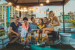 © oneinchpunch - Multiethnic group of young happy friends bonding and having party at home on a rooftop terrace with New York city view