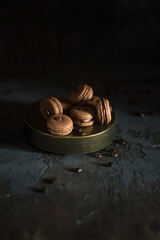 Wall Mural - Chocolate macarons on a dark background. Beautiful sweets for evening tea drinking.