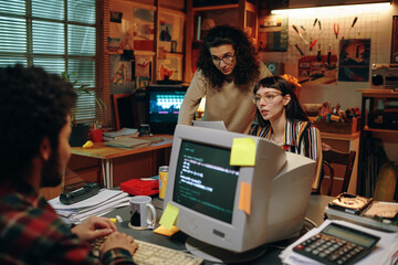 group of young people discussing new project together, they working on computer in garage