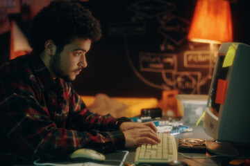 side view of young man typing codes on keyboard on computer to develop new software