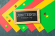 Juneteenth freedom day concept with colorful paper, blackboard and stars on black background. Top view, flat lay