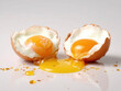 Two halves of broken egg with yolk splash, white background