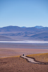 Canvas Print - Vertical view of a campervan on an off road road with a salt flat behind in the Bolivian Andes