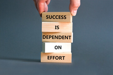 Wall Mural - Success and effort symbol. Concept words Success is dependent on effort on wooden block. Beautiful grey table grey background. Businessman hand. Business success and effort concept. Copy space.