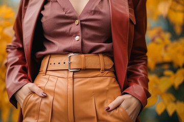 Wall Mural - Close up fashion details of dark brown classy leather jacket and orange pants with belt. Fancy women's clothing. Fashion cloth concept