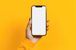 Hand holding a phone with a white screen with a yellow background