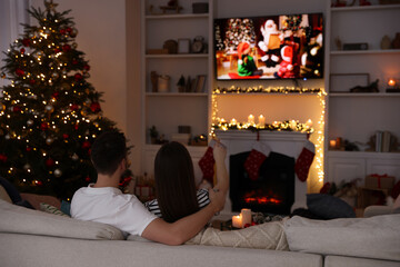 Sticker - Couple watching Christmas movie via TV in cosy room, back view. Winter holidays atmosphere