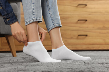 Wall Mural - Woman putting on white socks at home, closeup