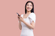 Asian businesswoman, showing smartphone, app interface recommending application on mobile phone, standing isolated over pink background.