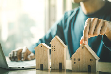 Wall Mural - Businessman choosing mini wood house model from model and row of coin money on wood table, selective focus, Planning to buy property. Choose what's the best. 