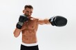 © SHOTPRIME STUDIO - Man athletic bodybuilder poses in boxing gloves with nude torso abs in full-length background, boxing and martial arts. Advertising, sports, active lifestyle, competition, challenge concept.