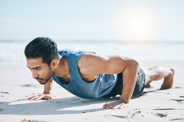 Man, beach and pushup on sand for workout, fitness or exercise for performance in summer sunshine. Young guy, bodybuilder and training for health, wellness and strong body with self care on ground