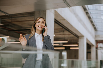 Wall Mural - Young business woman using mobile phone in the office hallway