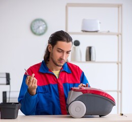 Wall Mural - Young male contractor repairing vacuum cleaner at workshop