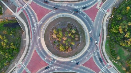 Wall Mural - Top view of city street traffic on roundabout intersection with moving cars. Viev from above of urban circular transportation crossroads
