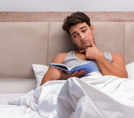 Wall Mural - Man reading book in the bed