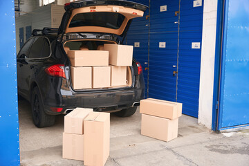 Wall Mural - Car with cardboard boxes in the trunk into a warehouse with self-storage unit