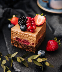 Wall Mural - Delicious chocolate cake decorated with fresh berries on stone black table