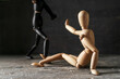 Wooden mannequins on table against dark background. Domestic violence concept