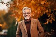 © Anne-Marie Albrecht - Portrait of a happy senior man in a coat and glasses standing in the autumn park.