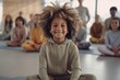 Cheerful little boy with Afro hairstyle looking at camera while sitting in yoga class