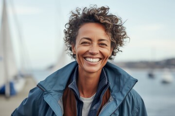 Wall Mural - Medium shot portrait photography of a cheerful woman in her 40s that is wearing a denim jacket against a dramatic sailboat race on a windy day background . Generative AI