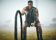 © Kirsten D/peopleimages.com - Fitness, battle rope and black man on field for power workout, body building and training muscle strength. Exercise, sports and African bodybuilder on grass with ropes, energy and outdoor performance